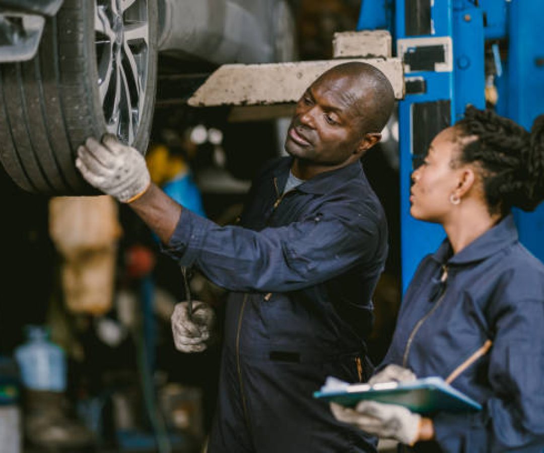 Auto garage worker Black African working together to fix service car vahicle wheel support together